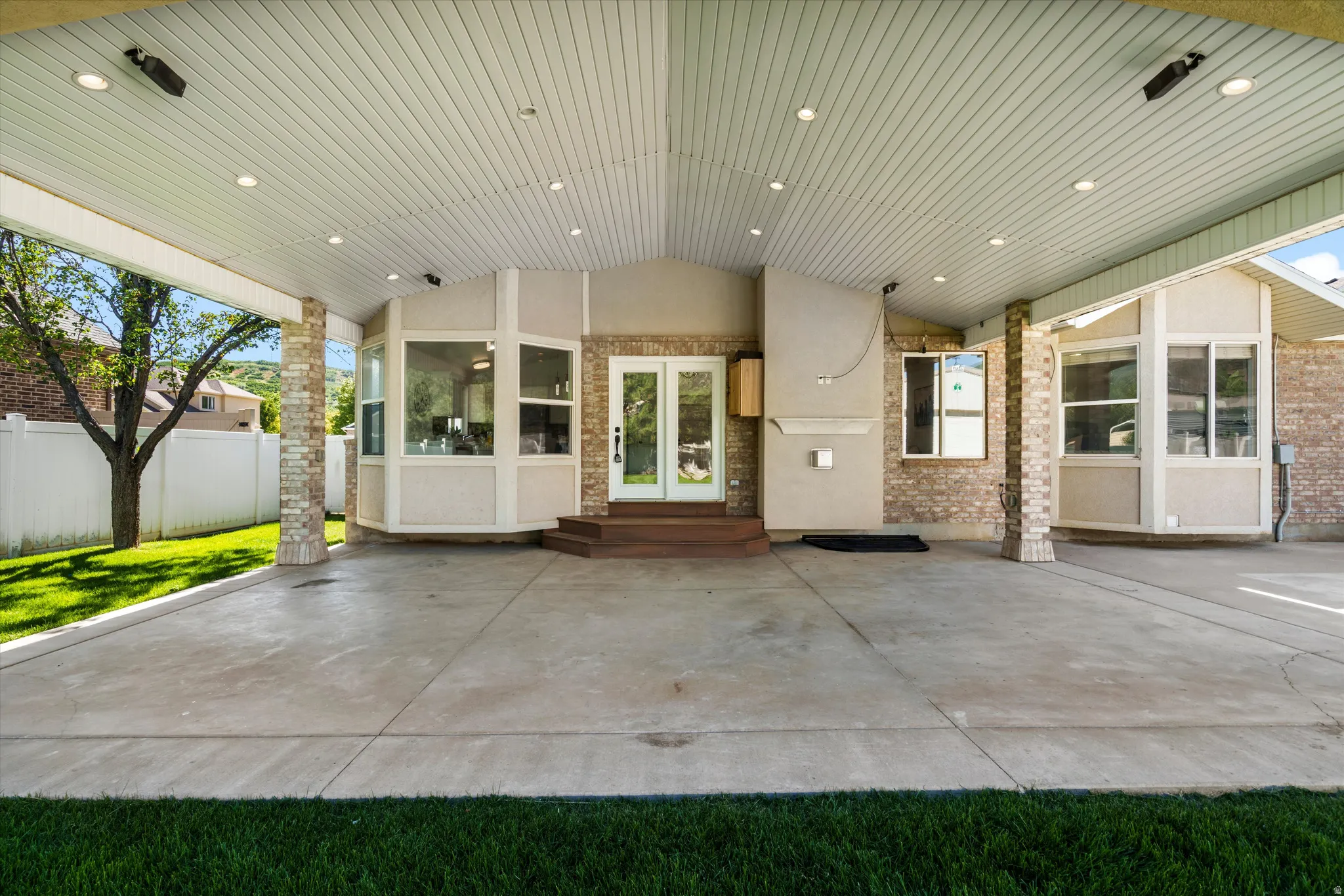 Expansive covered patio with recessed lighting and stamped concrete border.