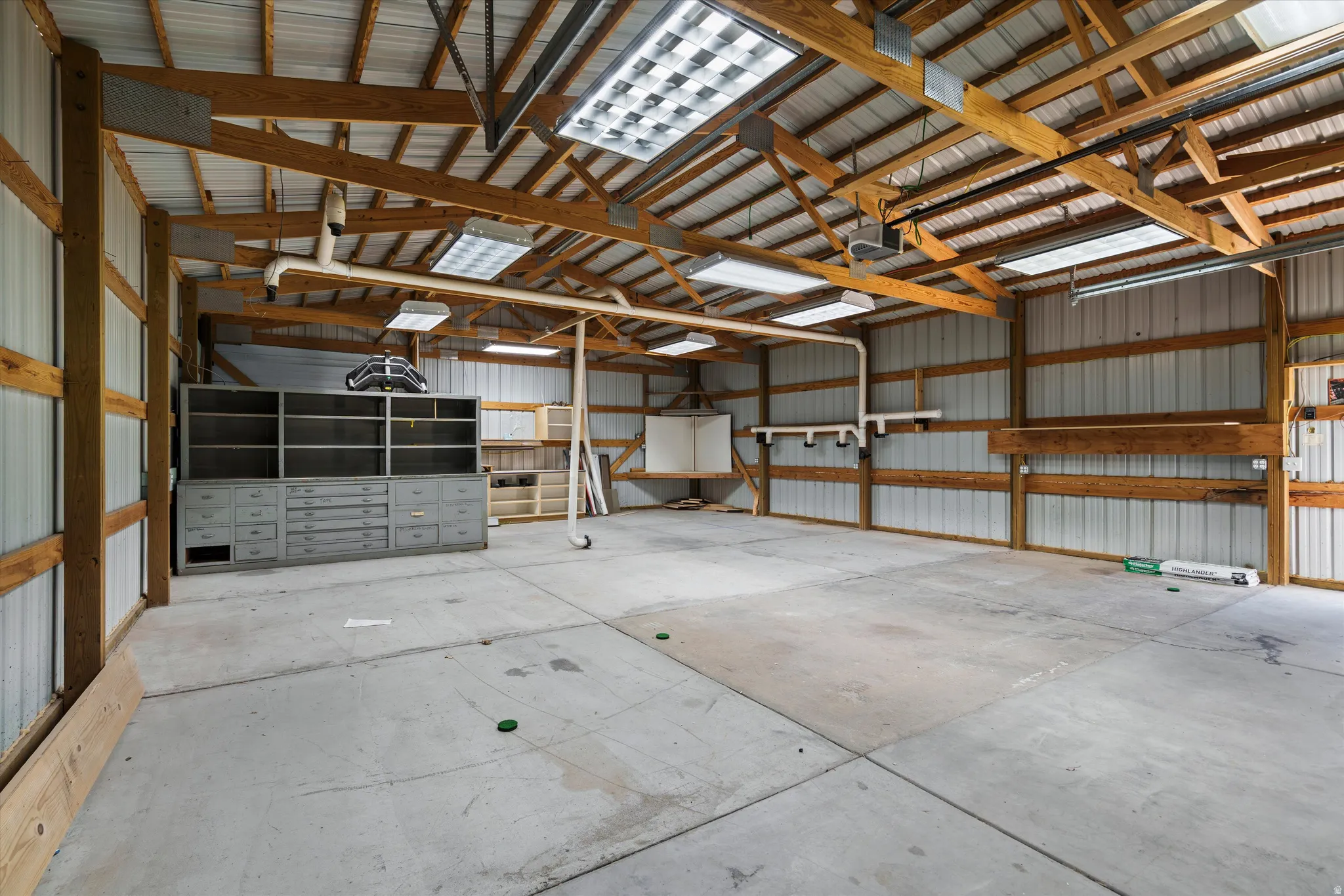 Spacious workshop building featuring a concrete floor, exposed wood beam construction, and corrugated metal walls