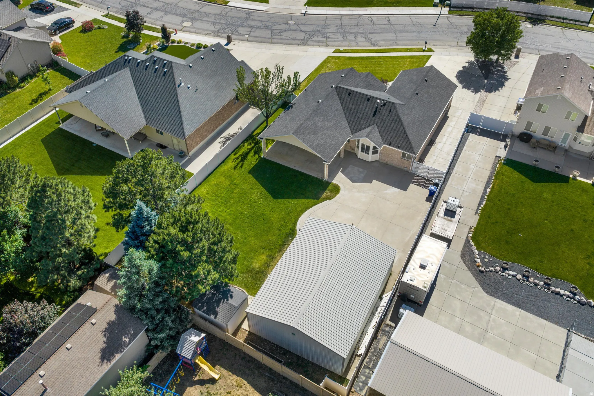 Expansive paved driveway leading to a two-story residence with an attached garage and a separate garage shop. RV Parking.