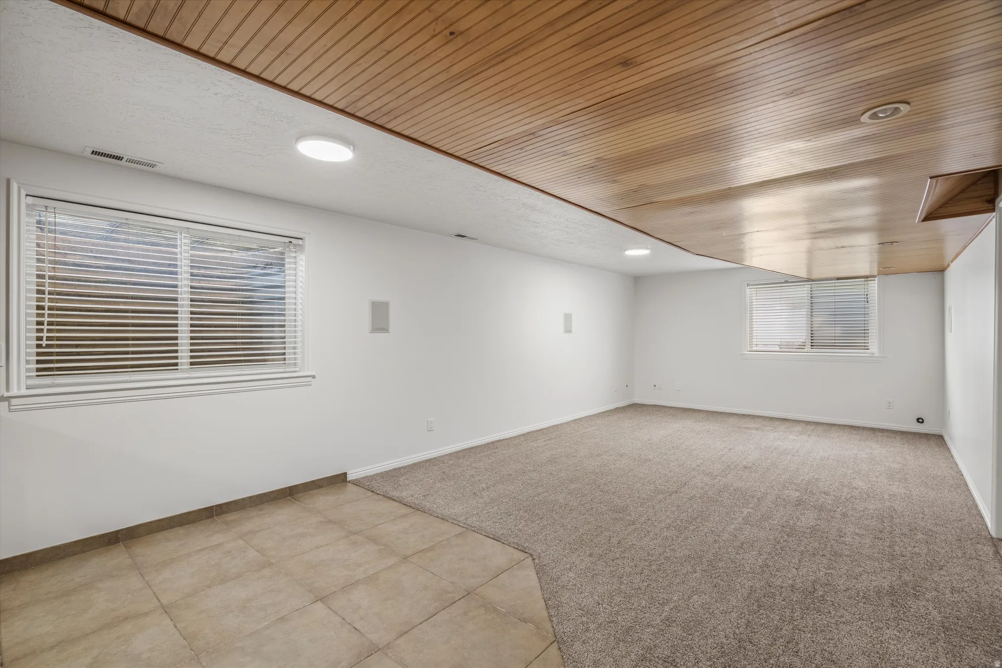 Dining and family room space next to kitchenette featuring a wood-finish ceiling, recessed lighting, and dual windows