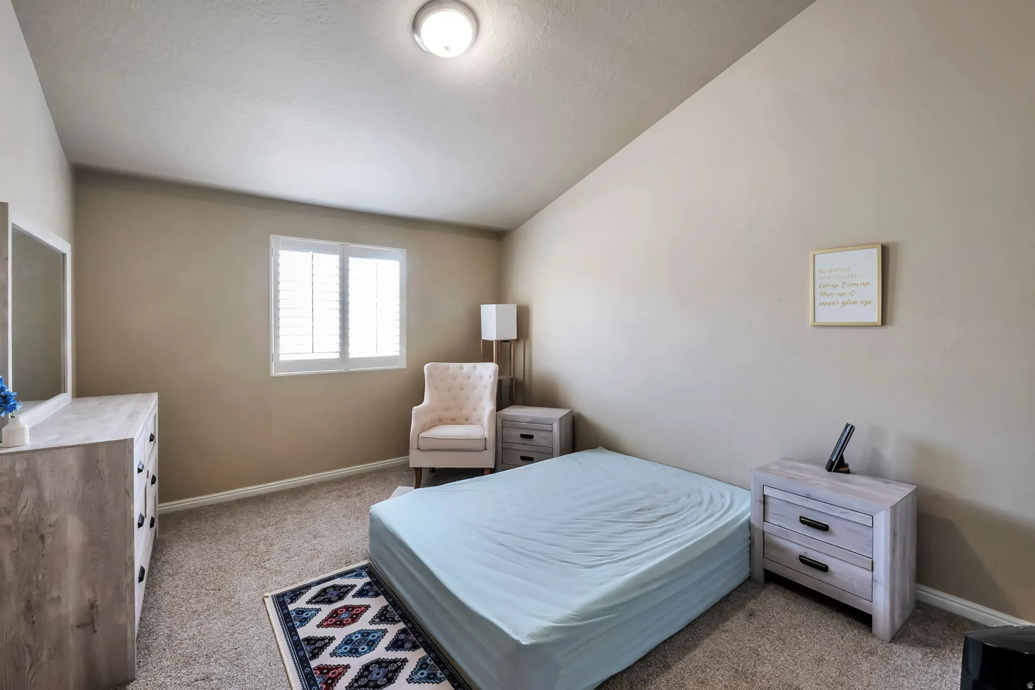 Carpeted room featuring a window with white louvered shutters, neutral wall tones, and a flush-mount ceiling light fixture