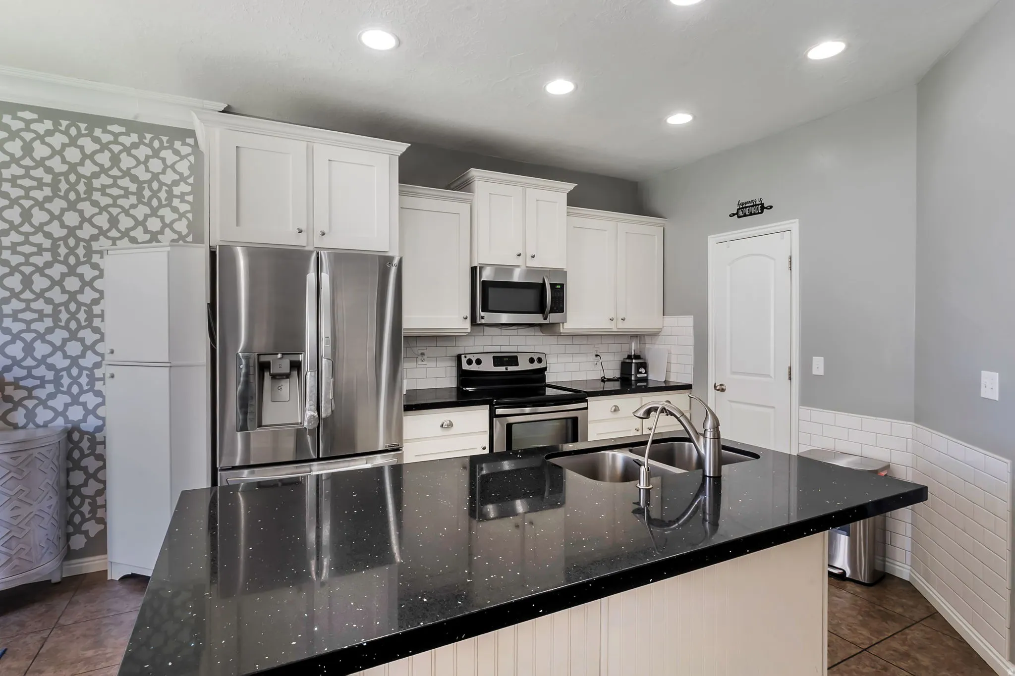 Kitchen featuring an island with a double basin sink and a black speckled countertop