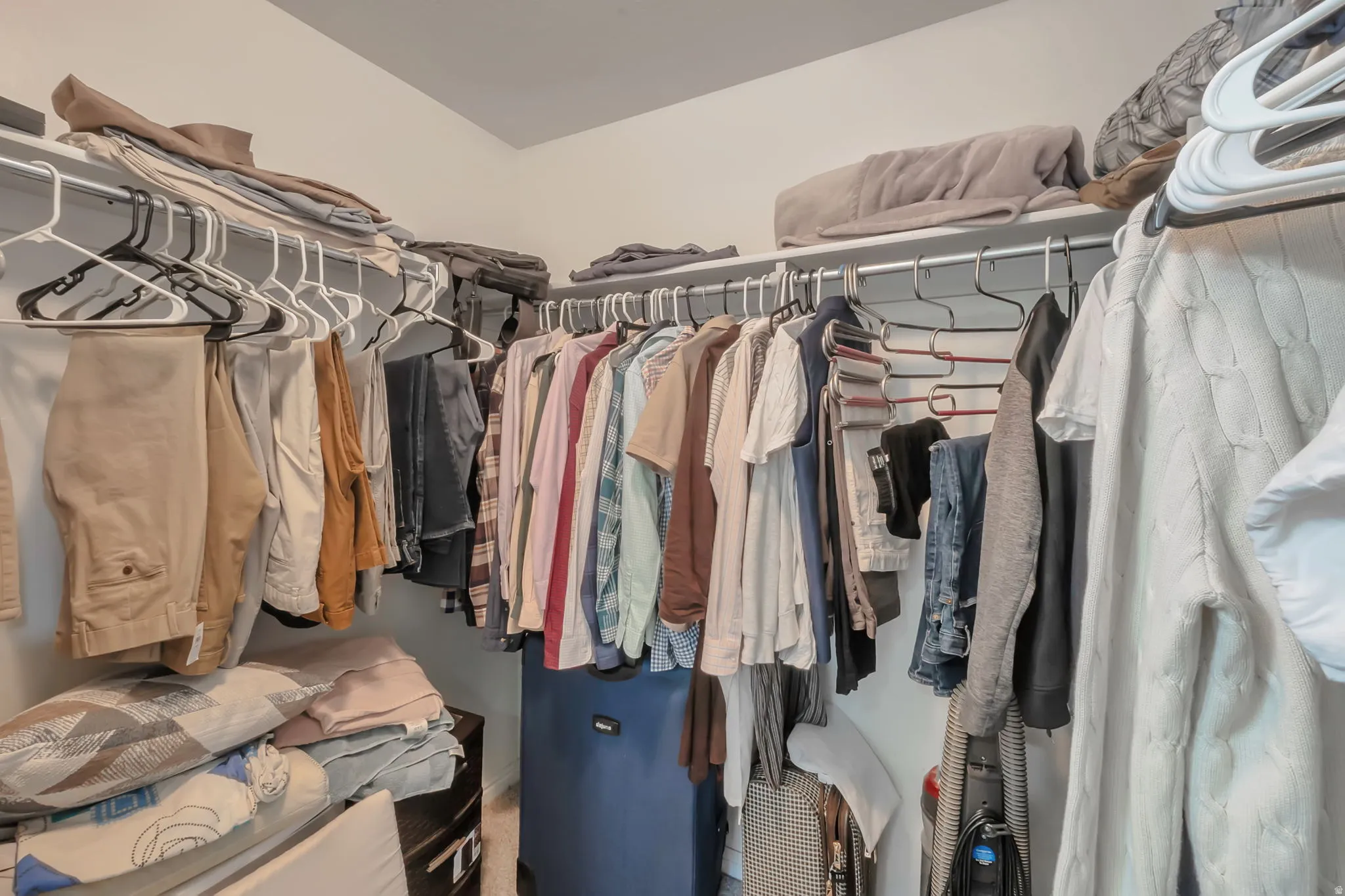 Walk-in closet featuring white walls, wire shelving, and chrome hanging rods