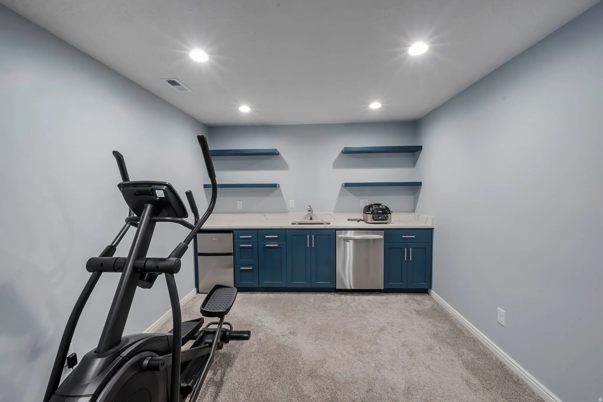 Dedicated flex space featuring a wet bar with dark blue cabinetry, a stainless steel sink, and a built-in dishwasher