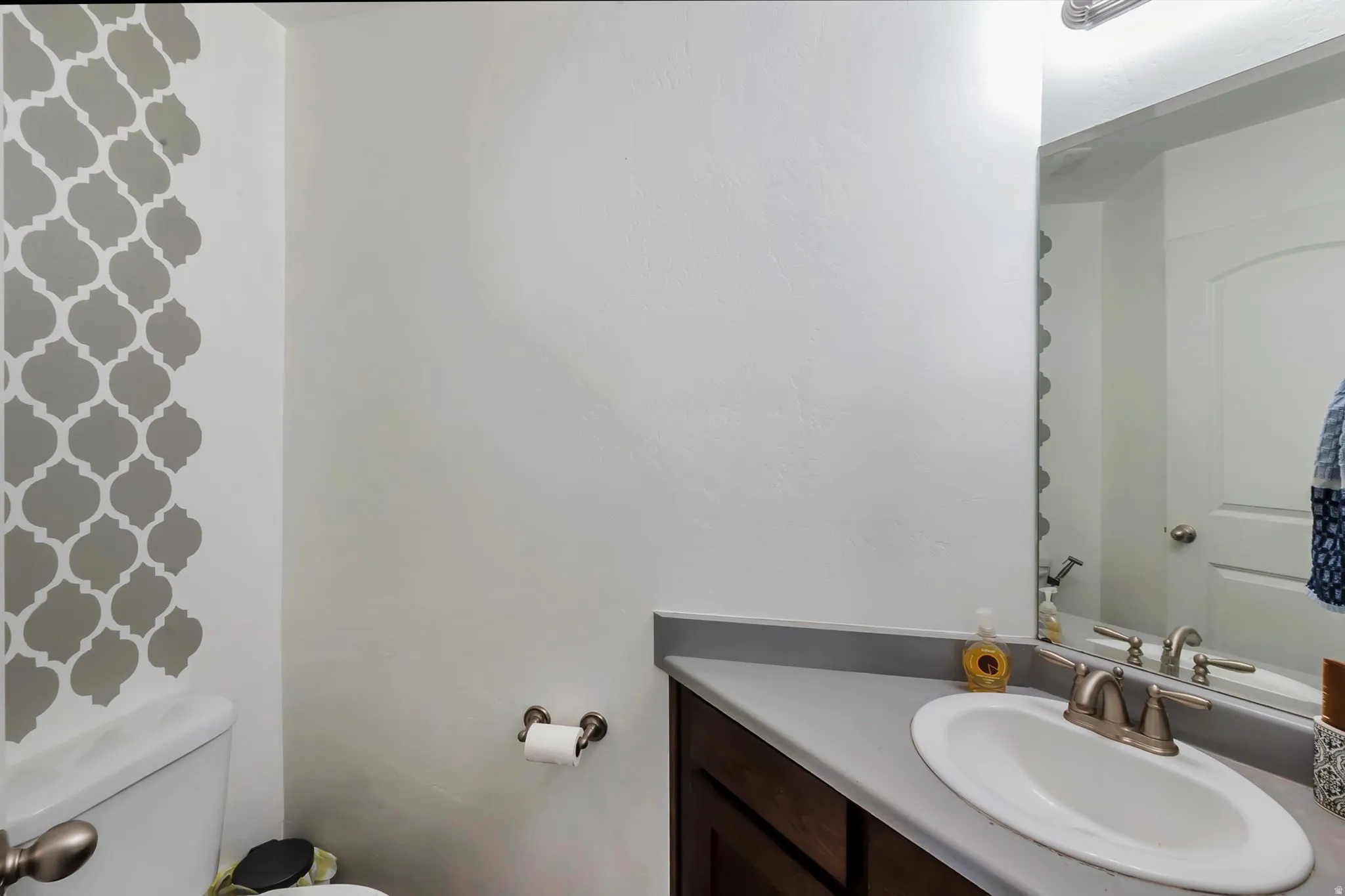 Bathroom vanity with a white oval sink, brushed nickel faucet, and a gray countertop