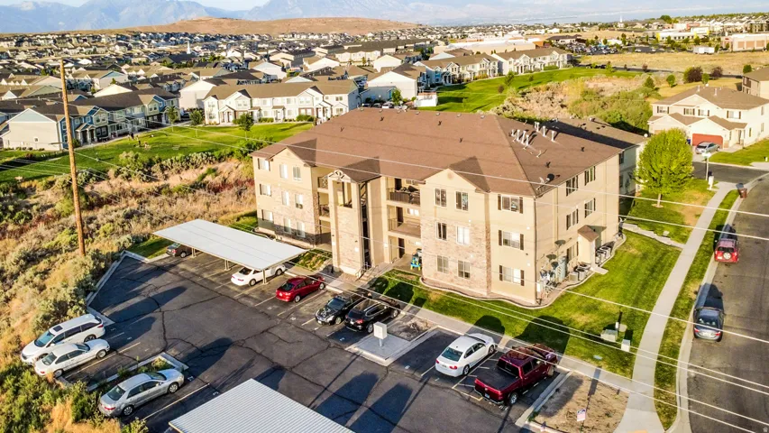 Three-story multifamily building with a stone and stucco facade, featuring multiple balconies and a pitched roof