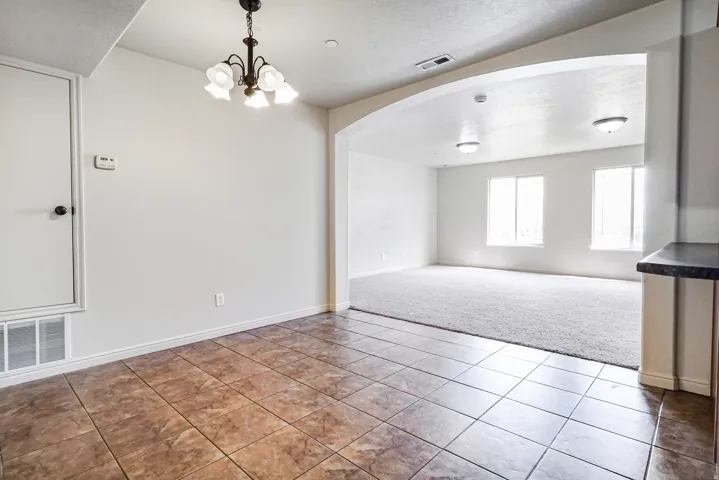 Tiled flooring, chandelier lighting, arched doorway, recessed lighting, carpeted flooring