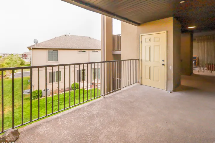 Outdoor balcony featuring a concrete floor, dark metal railings, and a panel door entry