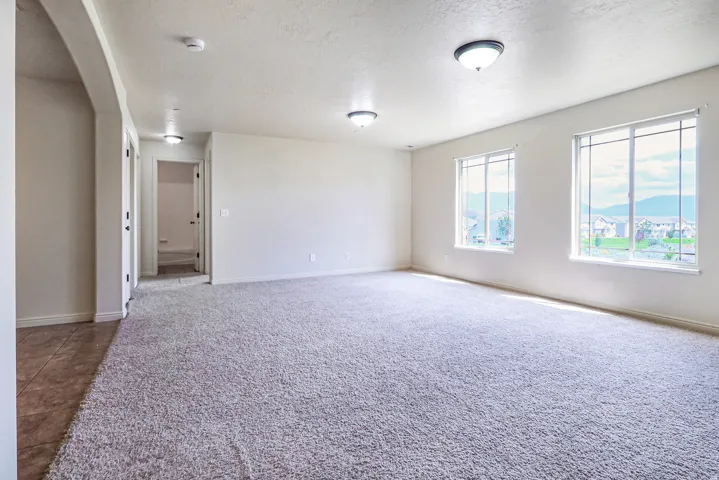 Spacious room featuring neutral carpeting, two large windows, and overhead flush-mount lighting
