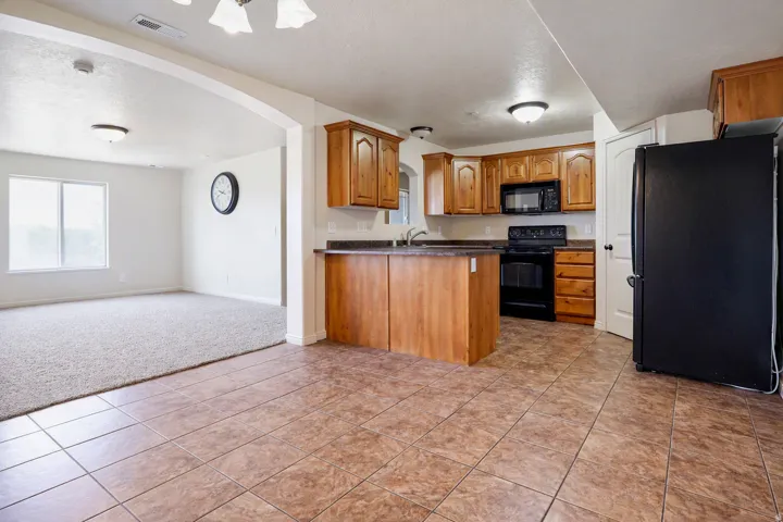 Kitchen featuring wood cabinetry, black appliances, and tile flooring