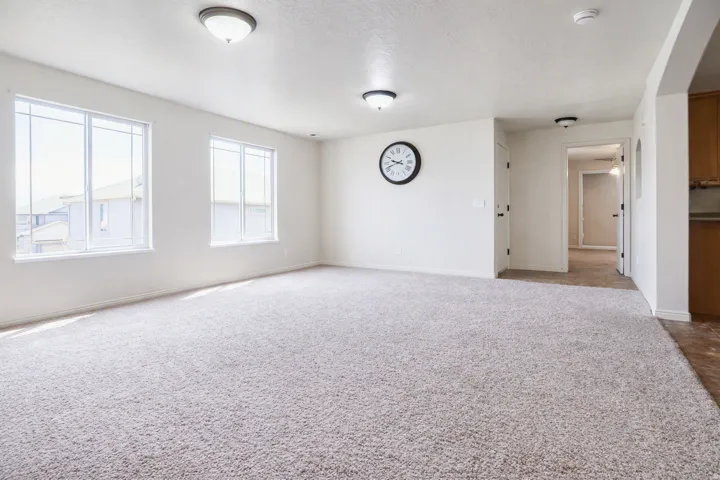 Plush carpeting, multiple windows, recessed lighting, and a neutral color palette