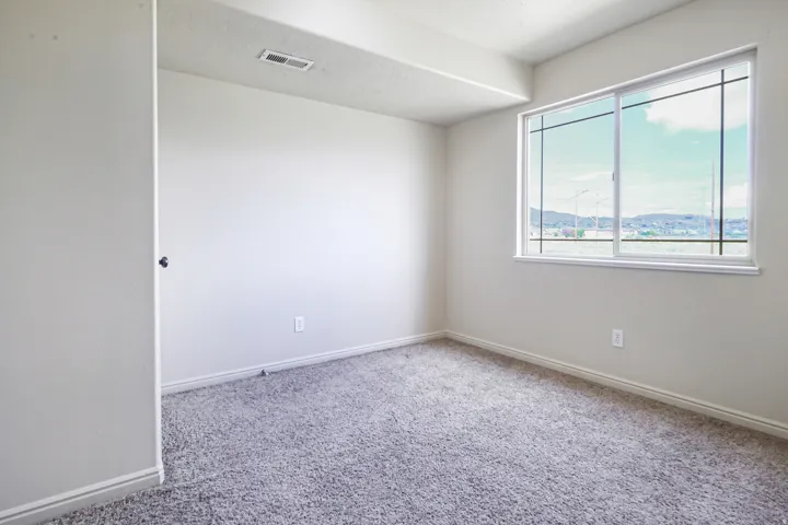 Textured gray carpeting, white painted walls, and a large window with white framing