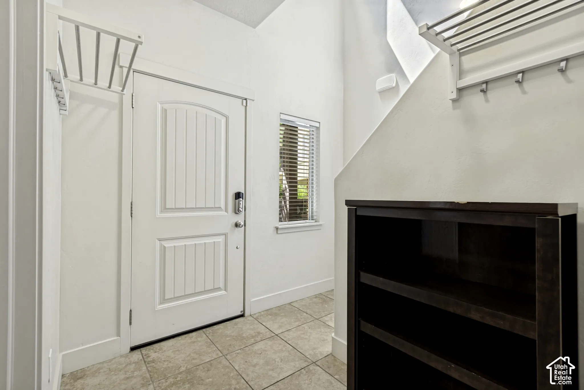 Entryway featuring a paneled door with smart lock, an adjacent window with horizontal blinds, and tile flooring