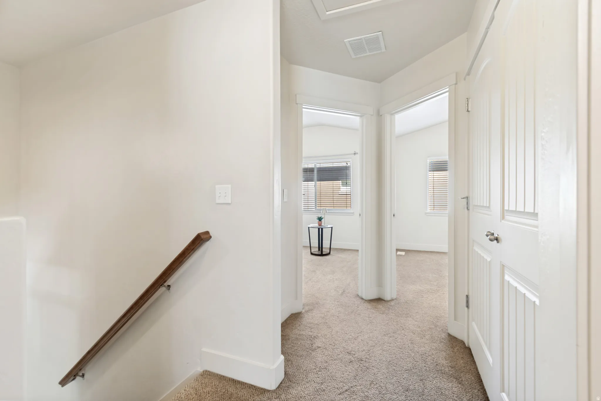 Neutral-toned corridor with plush carpeting, leading to multiple rooms