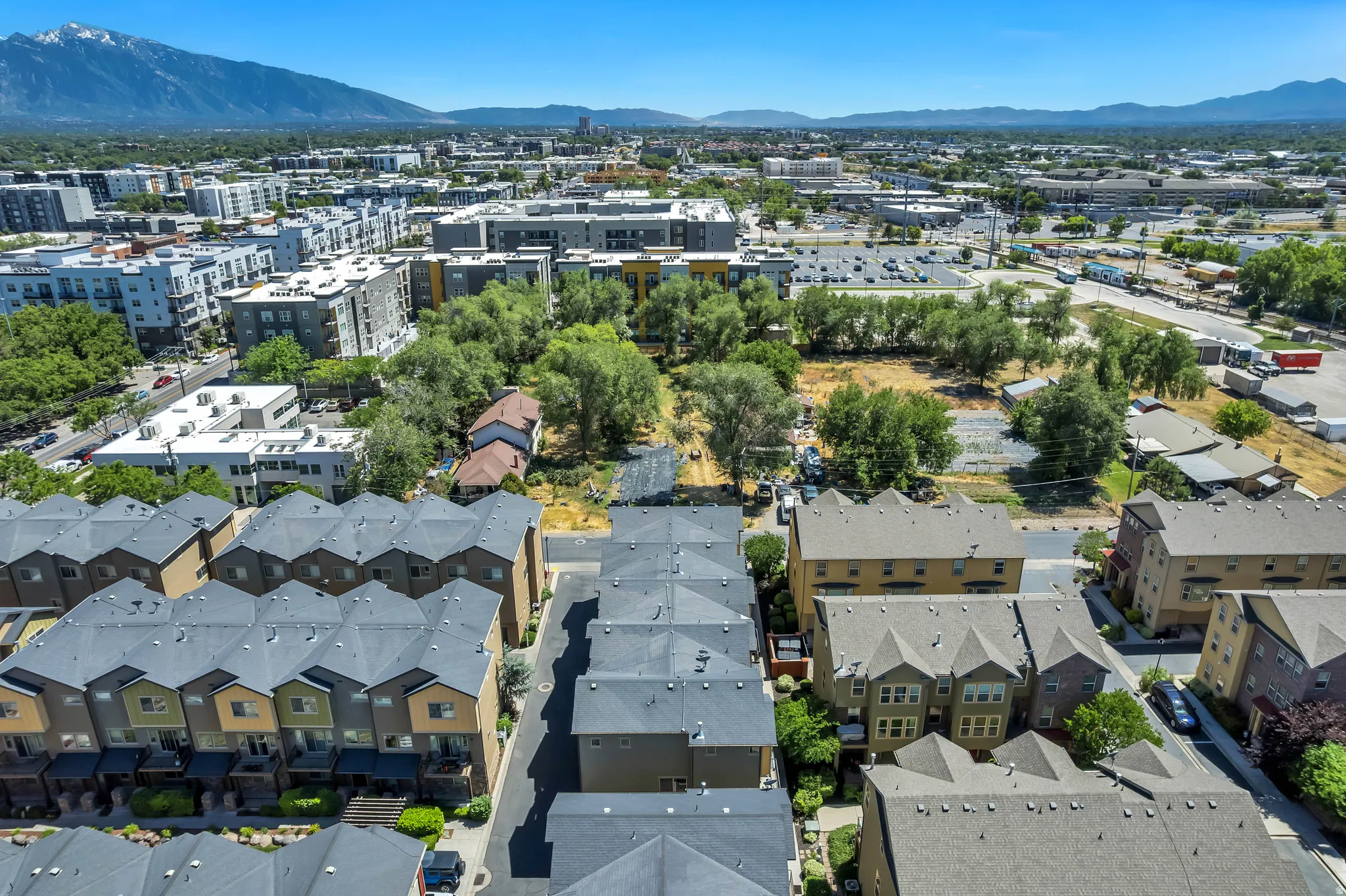 Townhome development featuring contemporary architecture with multi-story buildings, dark gray shingled roofs, and varied exterior siding colors