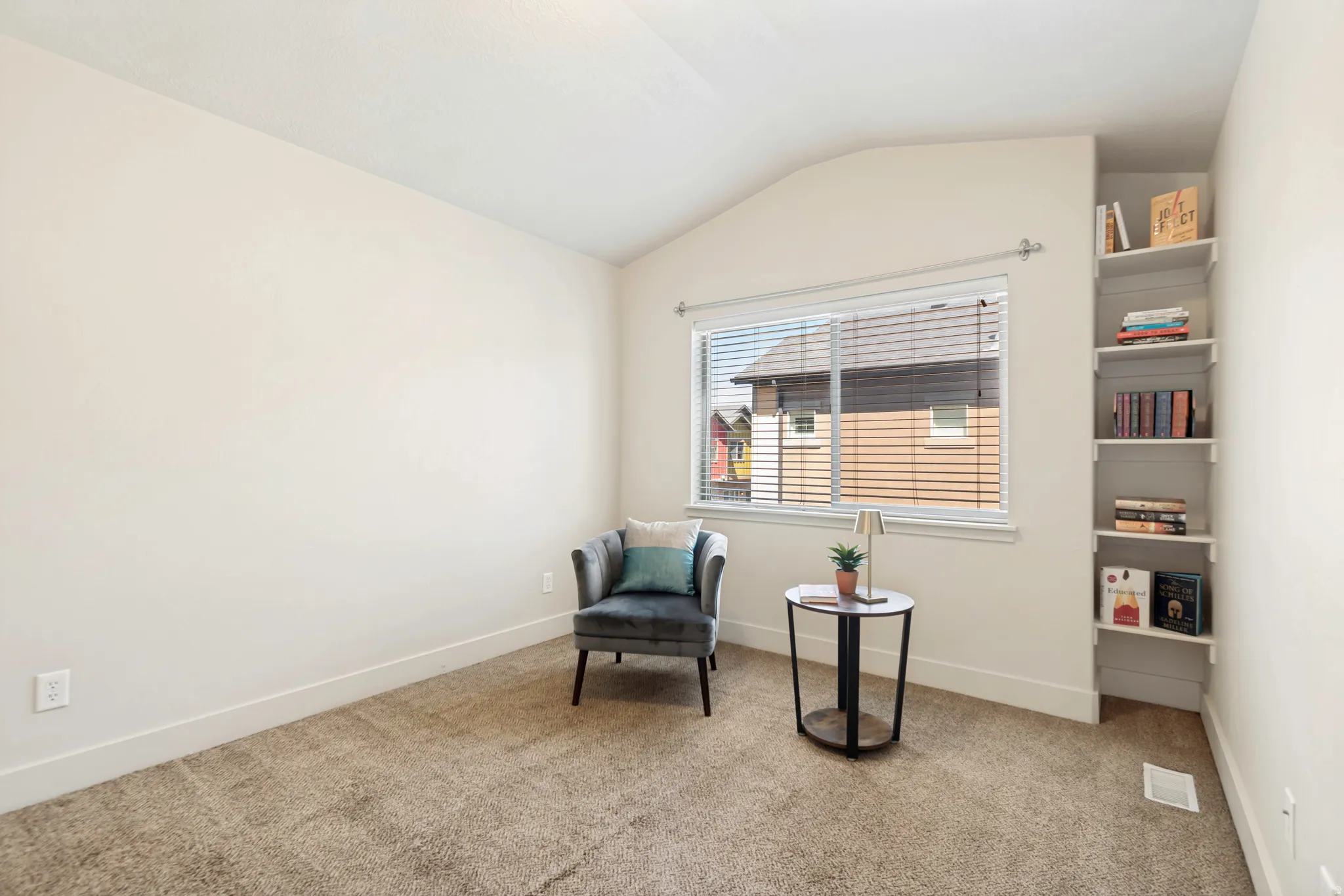 Carpeted room featuring a window with horizontal blinds, built-in shelving, white baseboards, and neutral wall paint