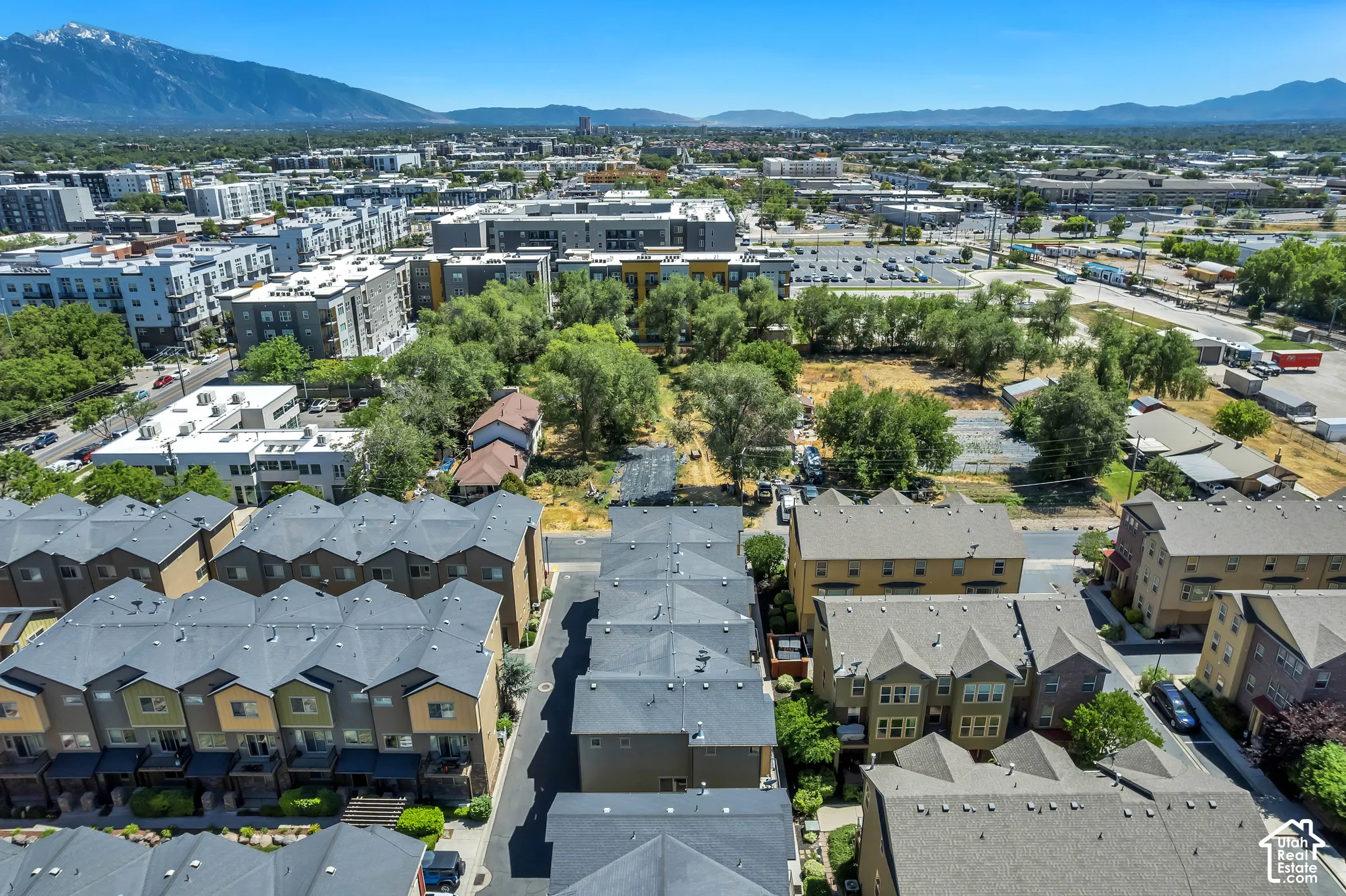 Townhome development featuring contemporary architecture with multi-story buildings, dark gray shingled roofs, and varied exterior siding colors