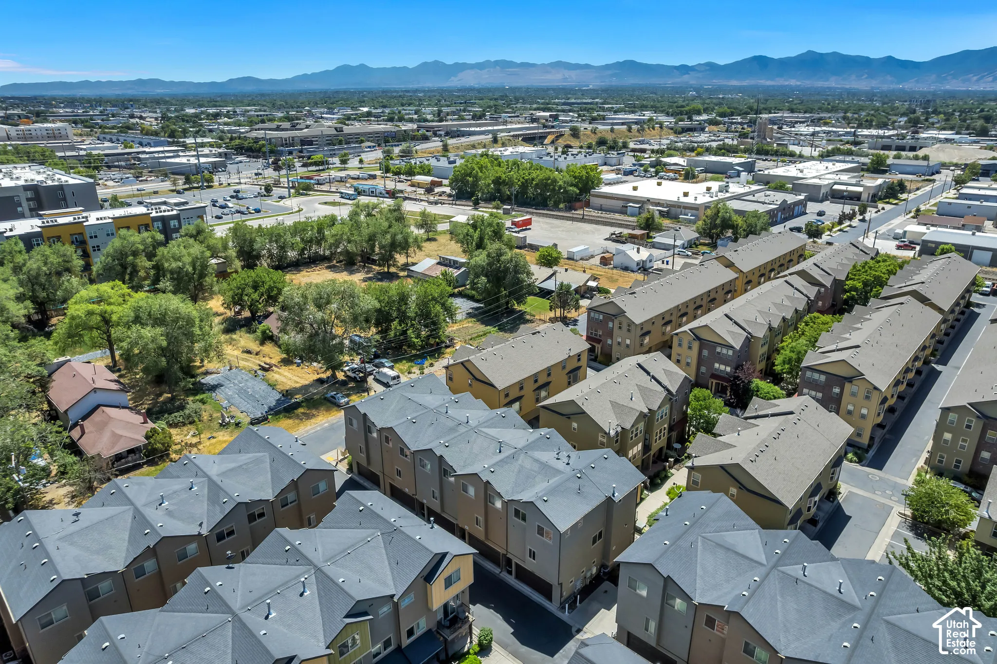 Aerial overview of a dense urban-suburban environment featuring multiple rows of multi-story townhomes, commercial buildings, and scattered green spaces