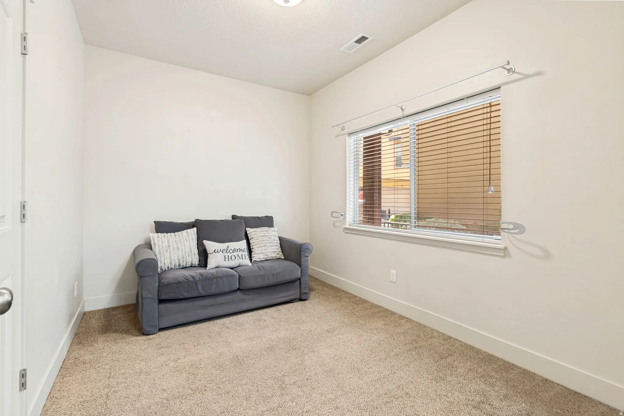 Carpeted room with a single window featuring horizontal blinds