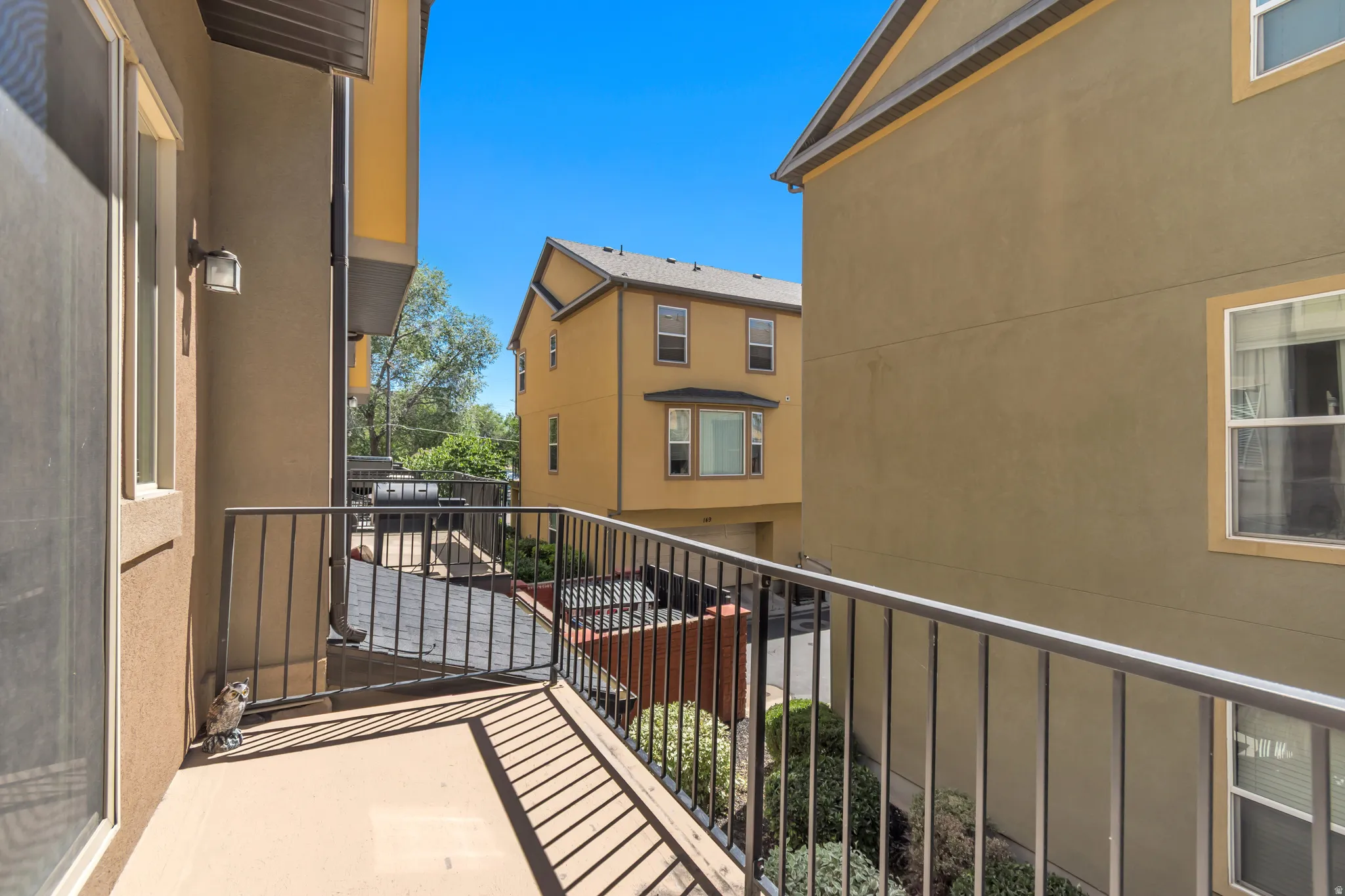 Exterior balcony featuring a stucco finish, metal railing, and an exterior wall sconce