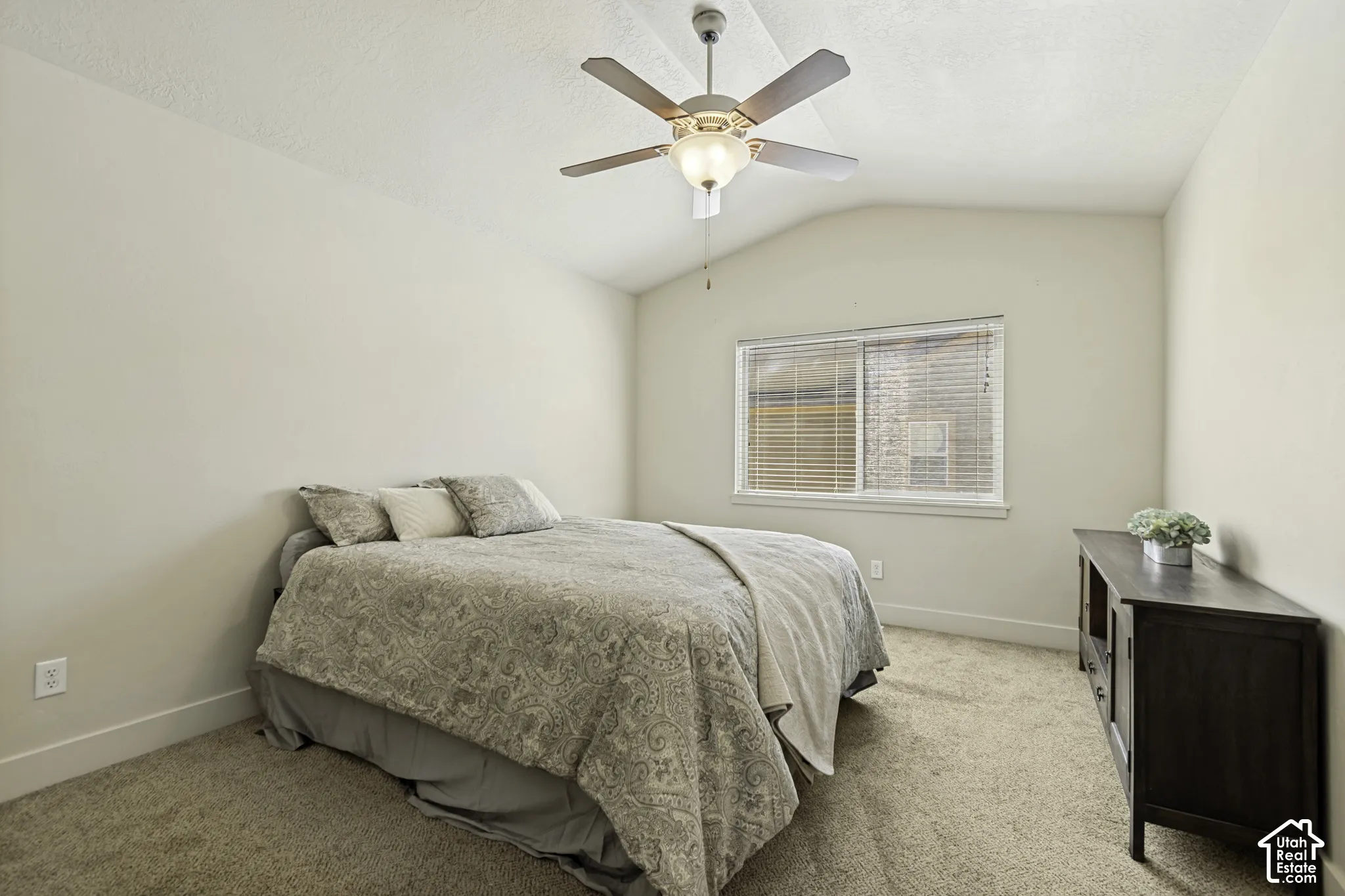 Vaulted ceiling bedroom with a ceiling fan, light-toned carpeting, and a window featuring horizontal blinds