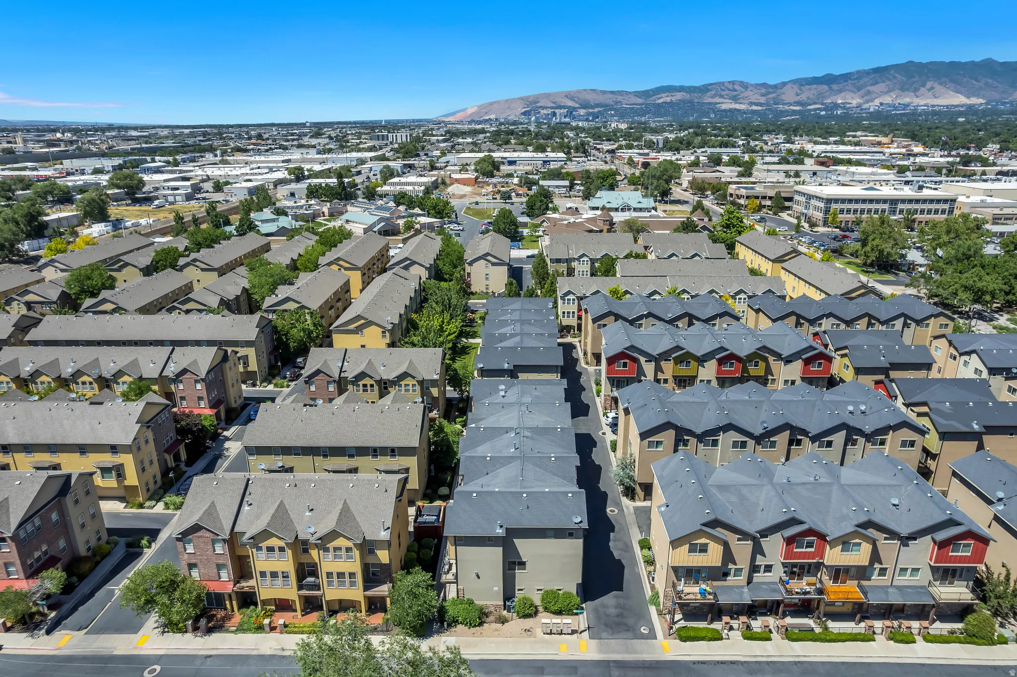 Aerial perspective showcasing multiple rows of multi-story townhomes with distinct gabled and hip roofs