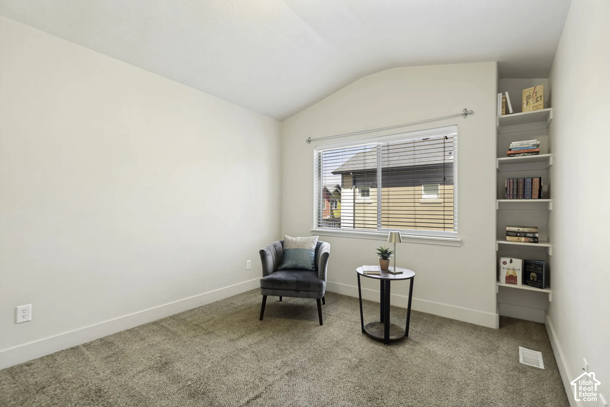 Carpeted room featuring a window with horizontal blinds, built-in shelving, white baseboards, and neutral wall paint