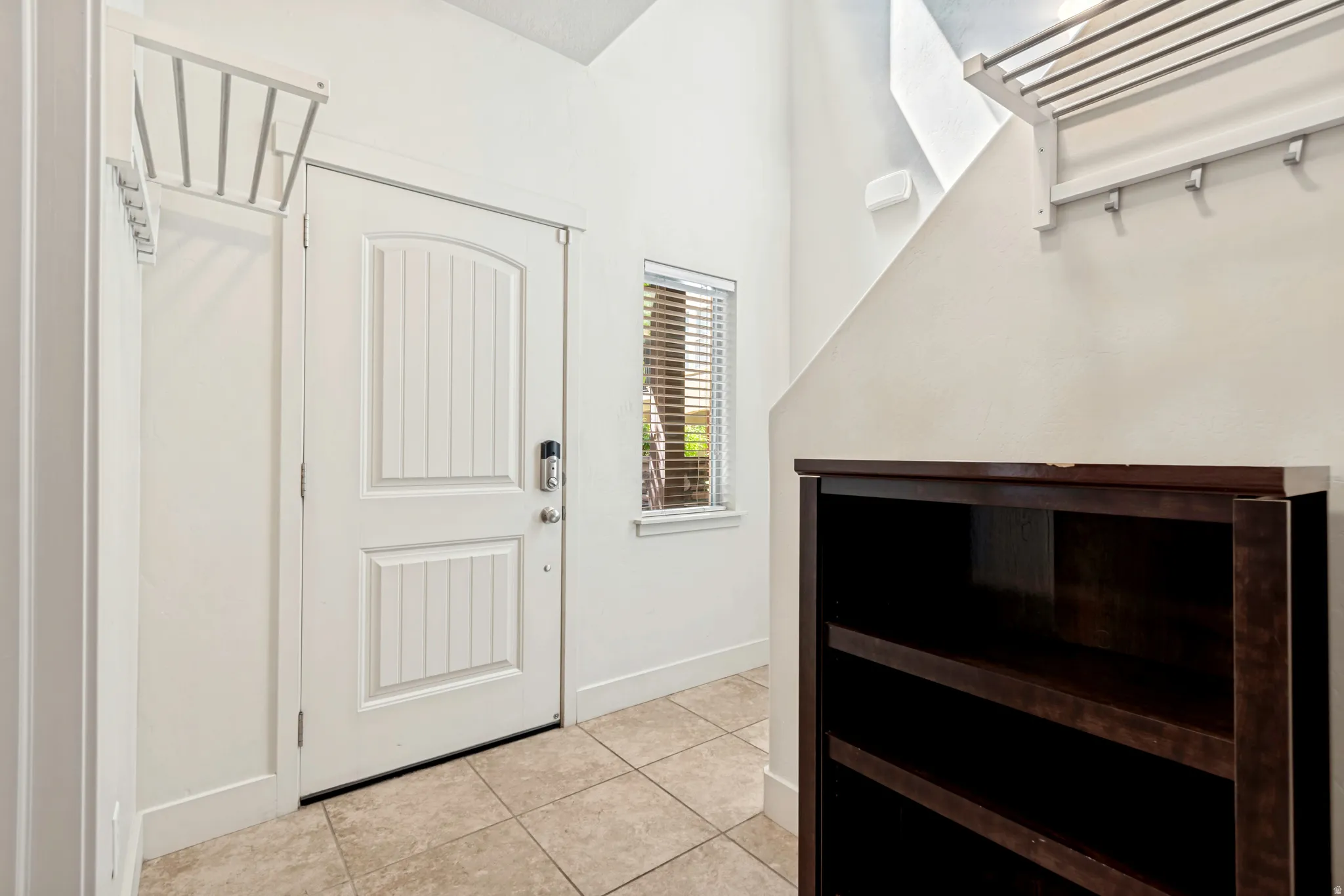 Entryway featuring a paneled door with smart lock, an adjacent window with horizontal blinds, and tile flooring