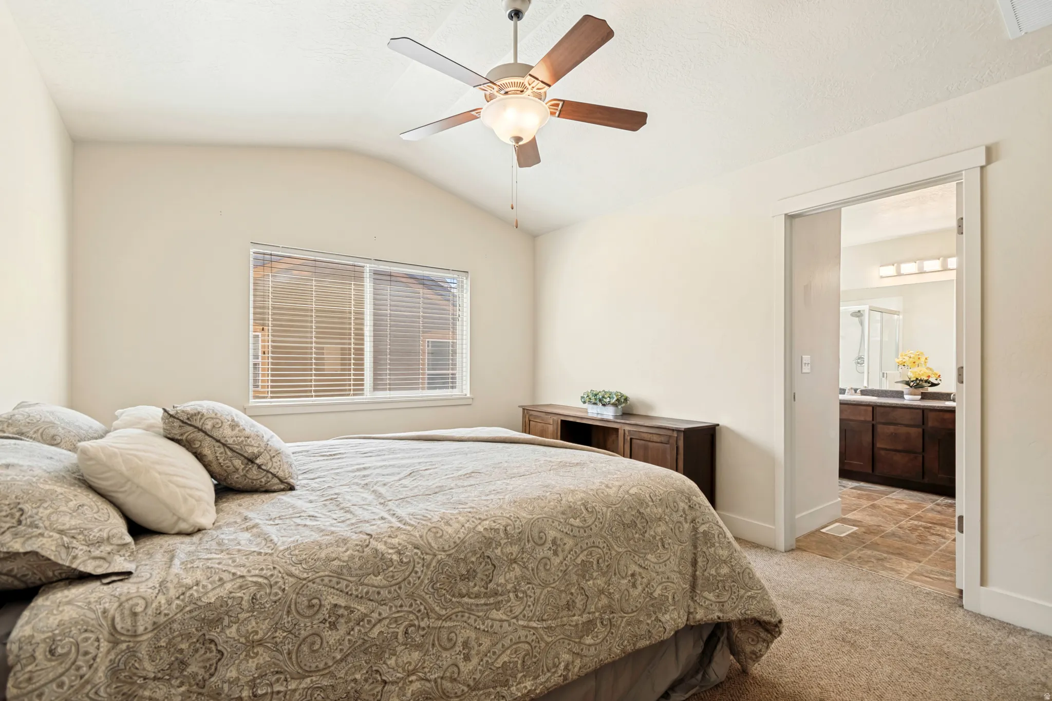 Vaulted ceiling bedroom featuring a ceiling fan with integrated lighting, window with blinds, and carpeted flooring