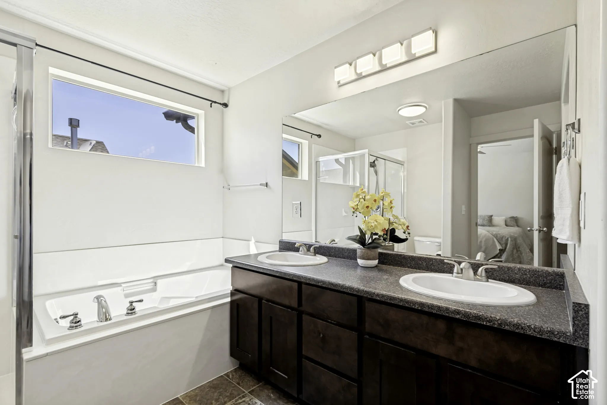 Dual vanity with undermount sinks, a large wall-mounted mirror, and a contemporary four-light fixture