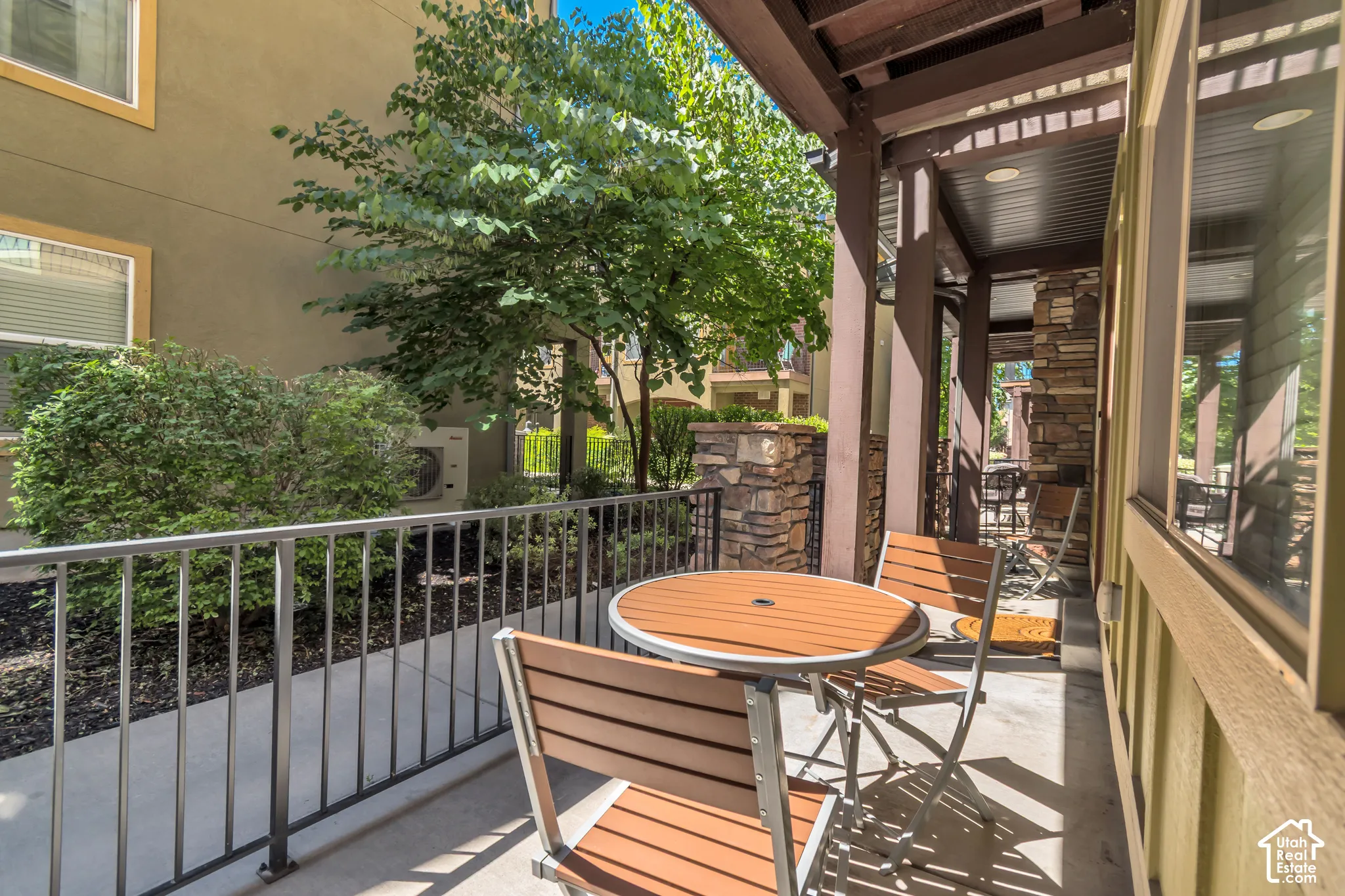 Covered patio with a metal railing and concrete flooring