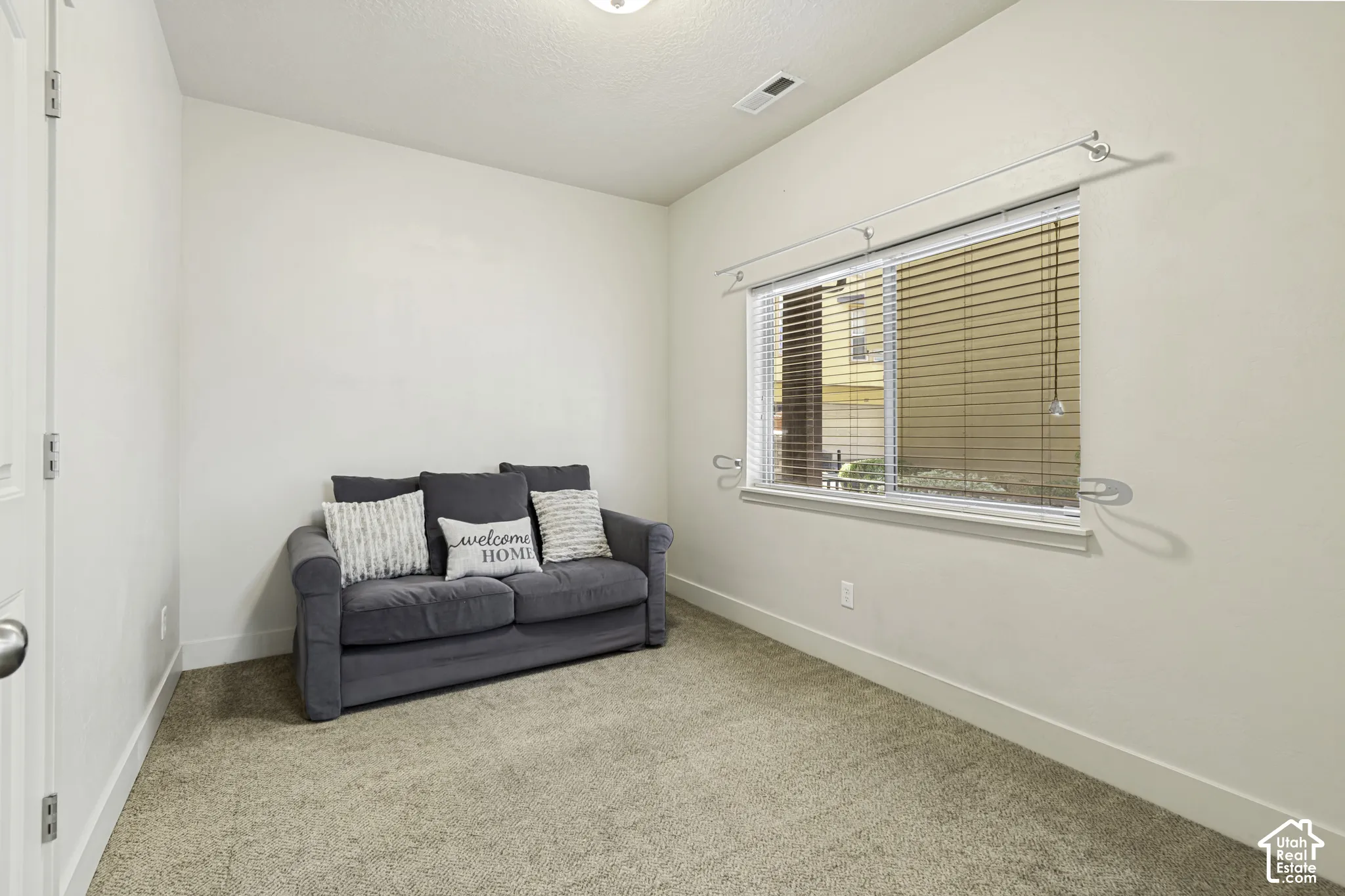 Carpeted room with a single window featuring horizontal blinds