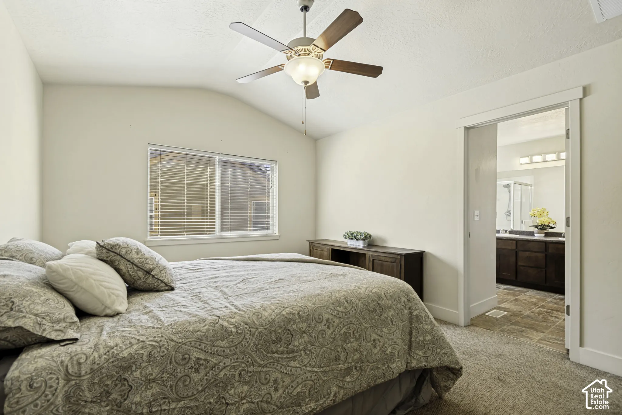 Vaulted ceiling bedroom featuring a ceiling fan with integrated lighting, window with blinds, and carpeted flooring