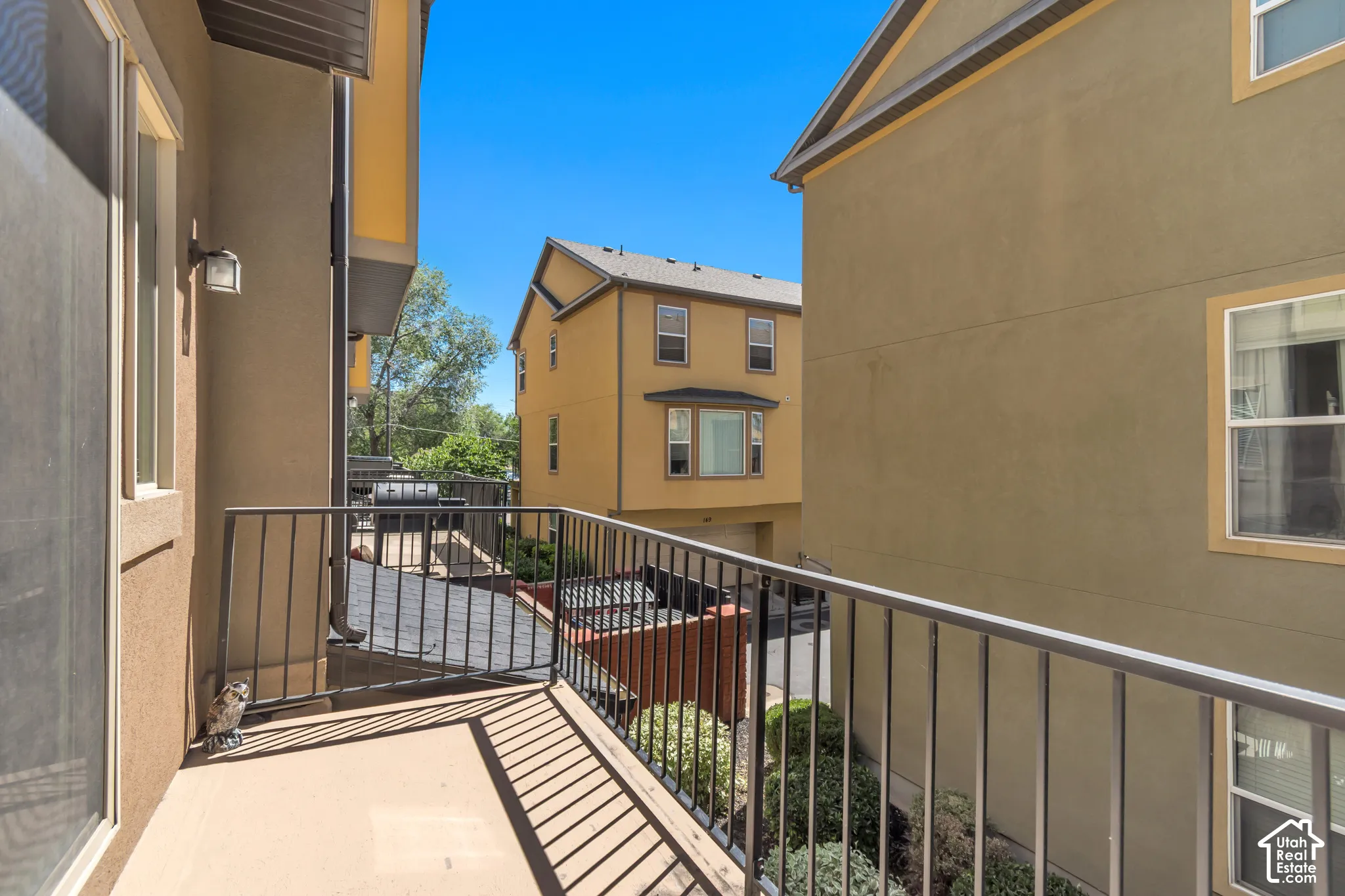 Exterior balcony featuring a stucco finish, metal railing, and an exterior wall sconce