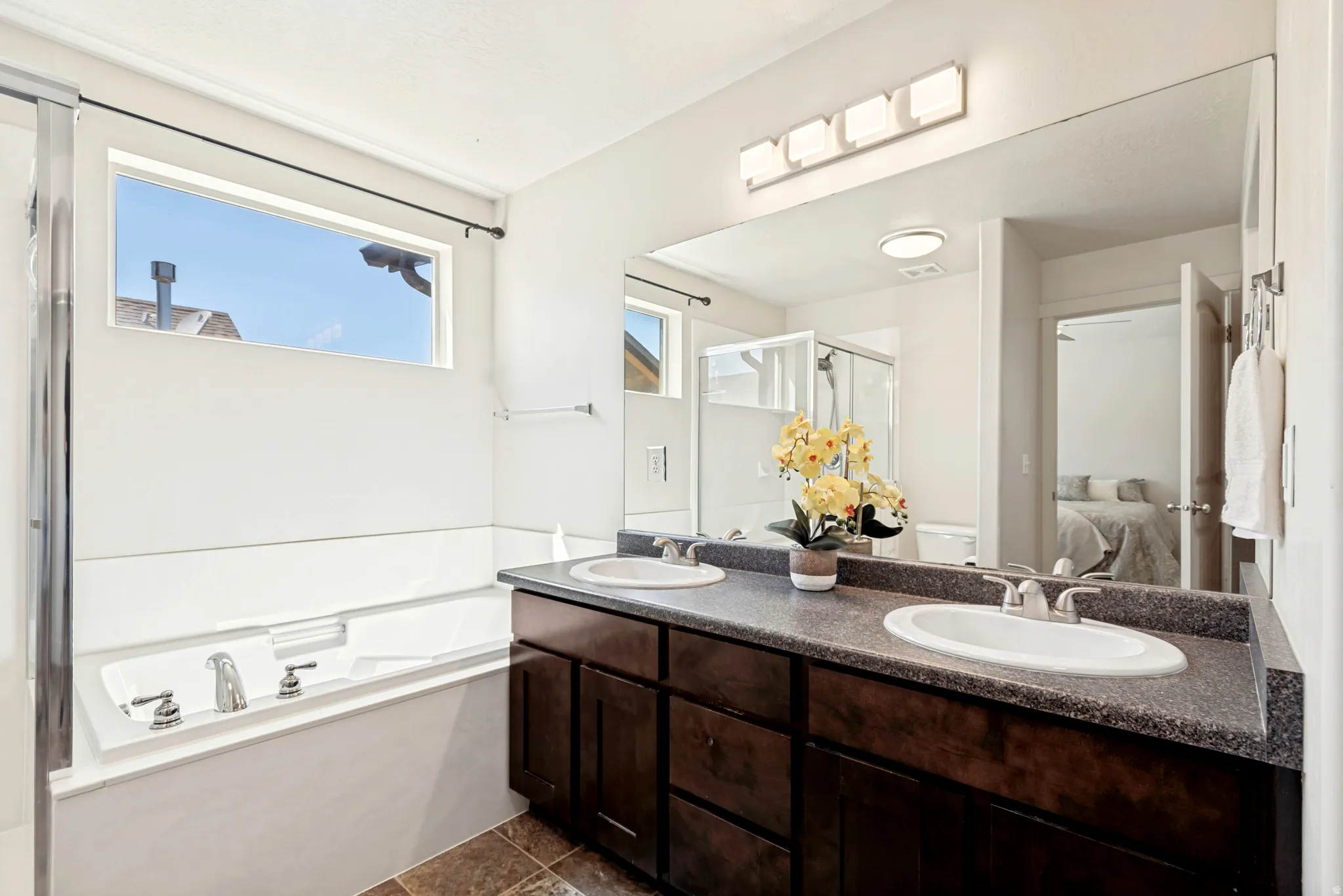 Dual vanity with undermount sinks, a large wall-mounted mirror, and a contemporary four-light fixture