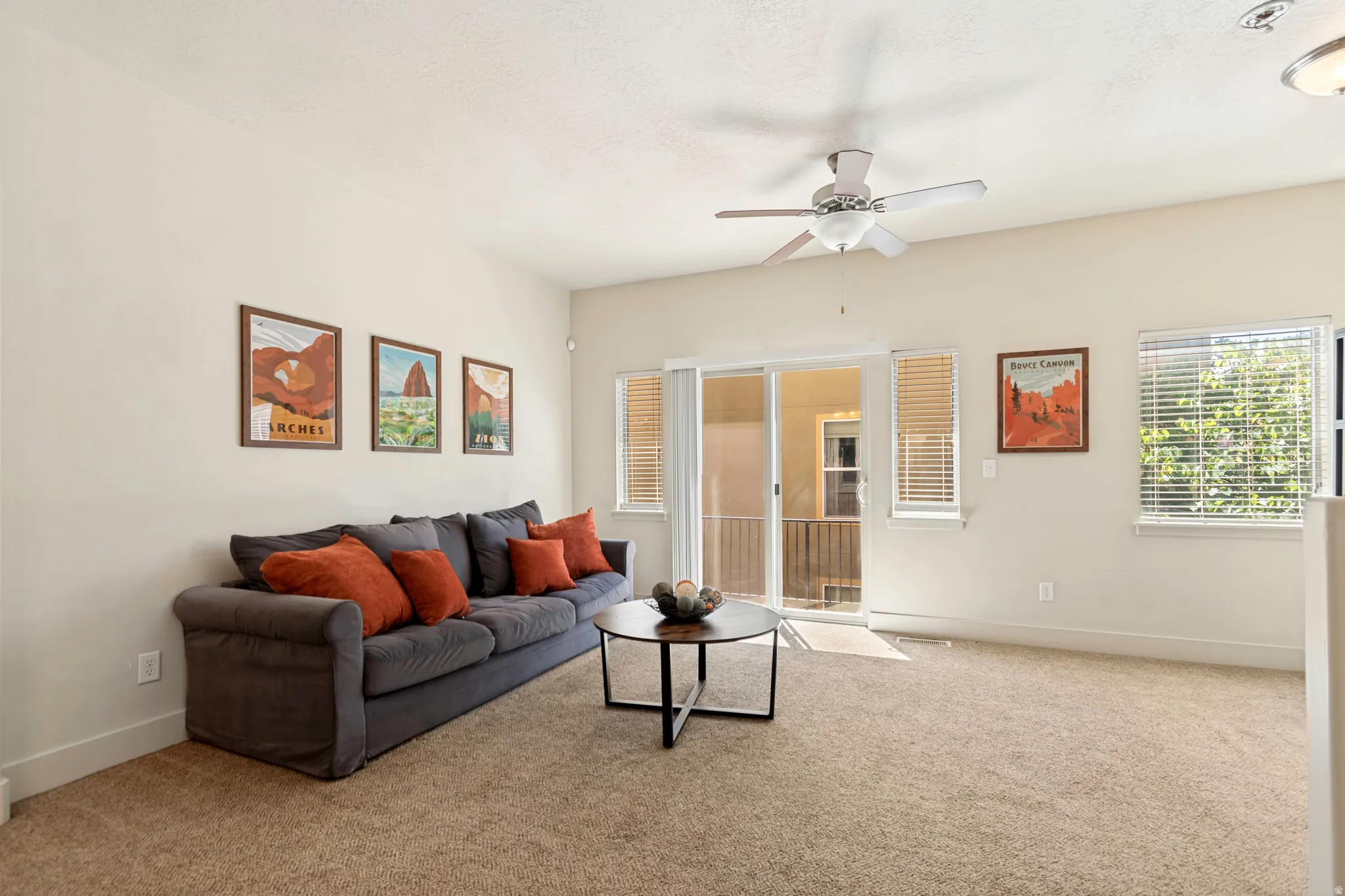 Carpeted living space featuring light-toned walls, a ceiling fan, and white trim