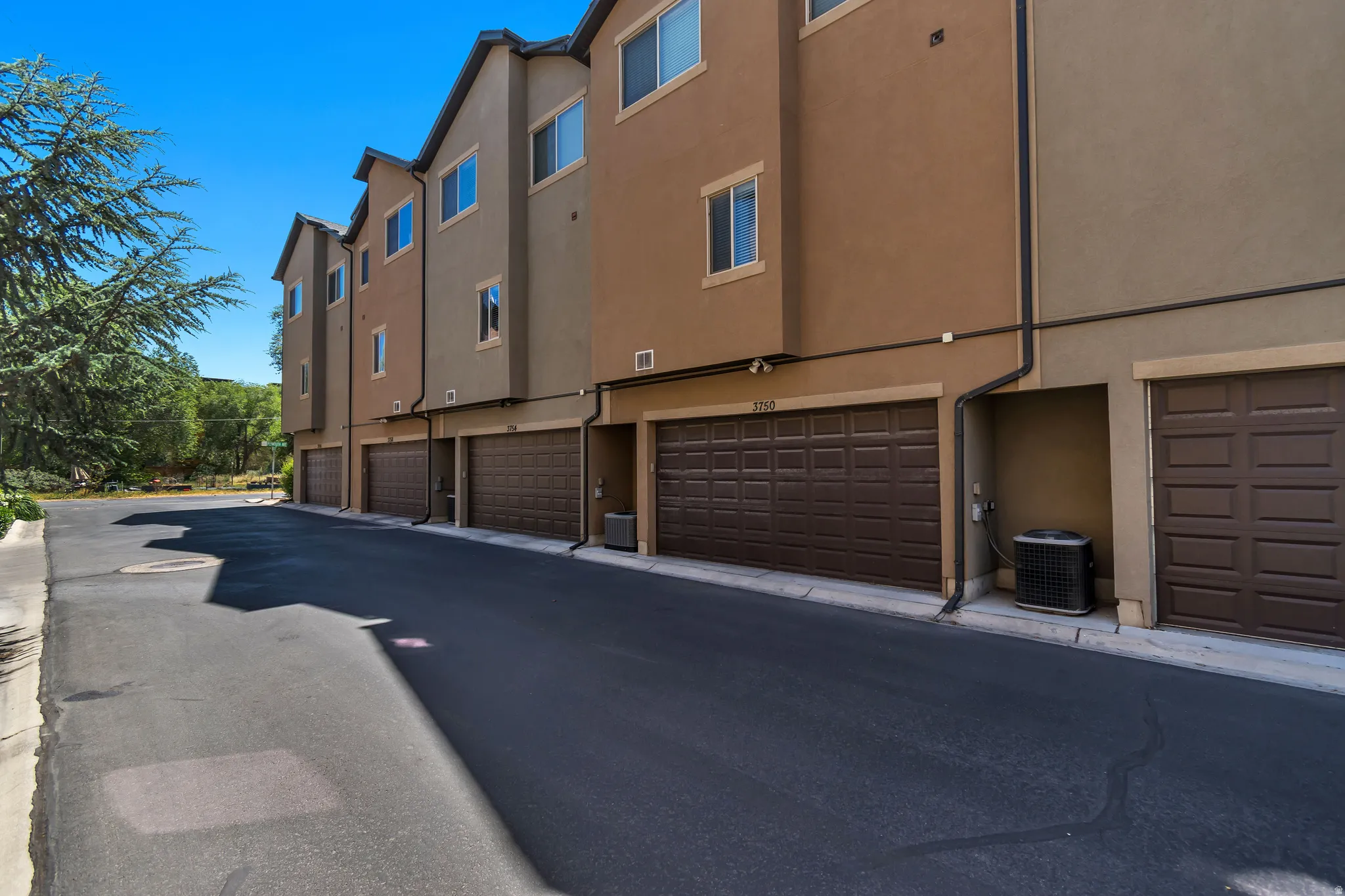 Multi-level residential exterior featuring stucco siding and individual attached garages