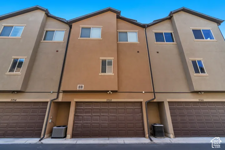 Multi-story stucco exterior featuring three-level architectural design, integrated multi-car garage doors, and grid-frame windows