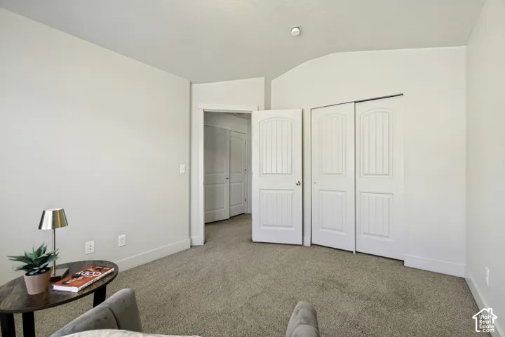 Carpeted interior space featuring neutral wall tones, white trim, a double-door closet with paneling, and an additional interior doorway