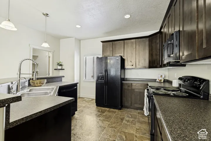 Kitchen featuring dark wood-finish cabinetry, black appliances, a double basin stainless steel sink with a high-arc faucet, and mottled gray countertops