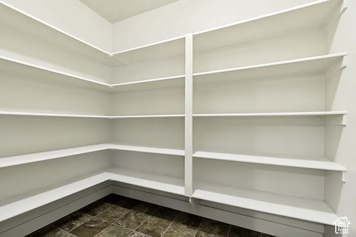Expansive pantry featuring multi-level built-in shelving, white painted finishes, and durable tile flooring