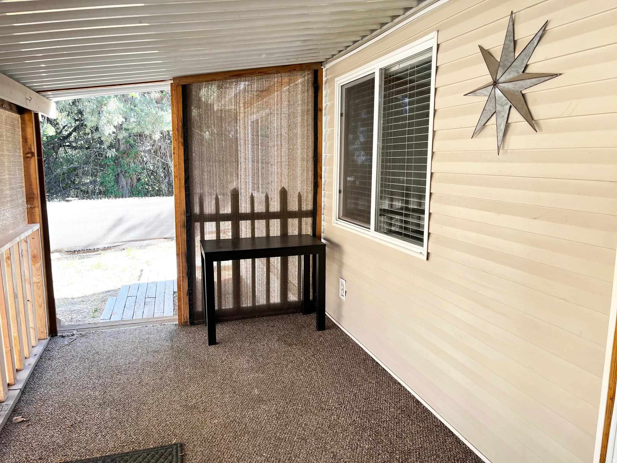 Enclosed outdoor space featuring a textured carpet floor, a horizontal slat ceiling, and a window with horizontal blinds