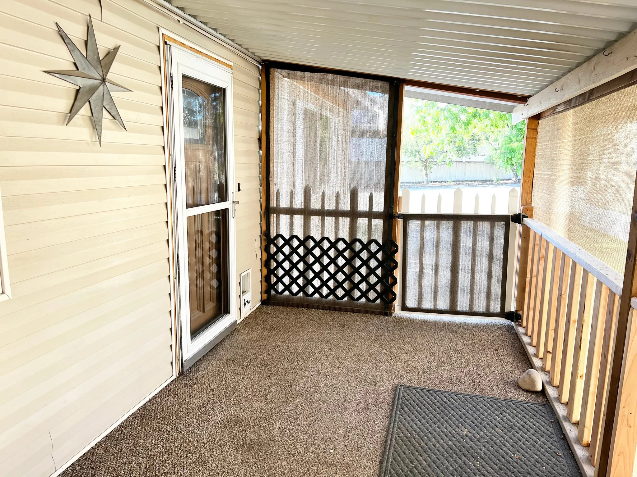 Screened porch featuring wood-finish railing, privacy screening, and a textured outdoor carpet