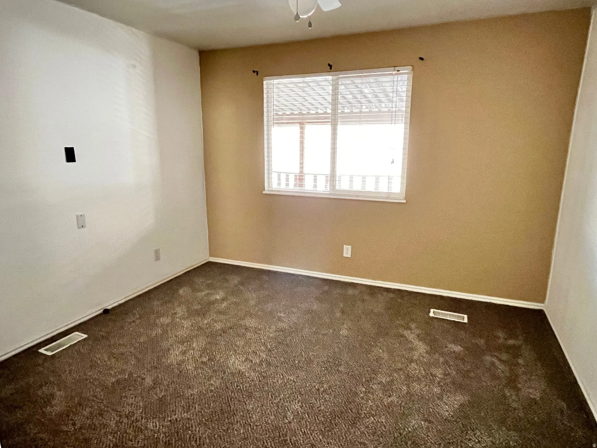 Carpeted room with a window featuring blinds and a white frame