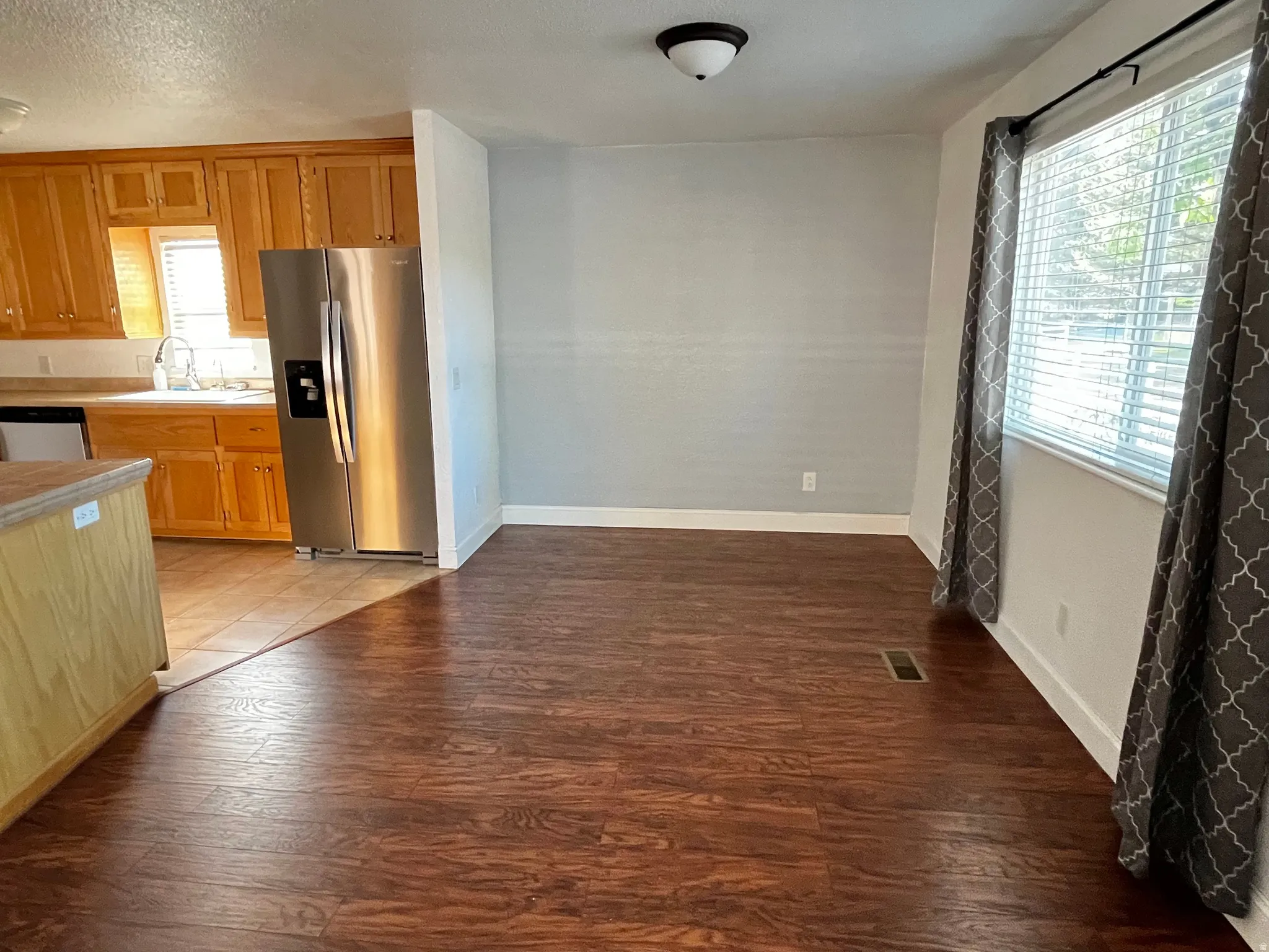 Spacious interior featuring wood-finish flooring and a large window with blinds