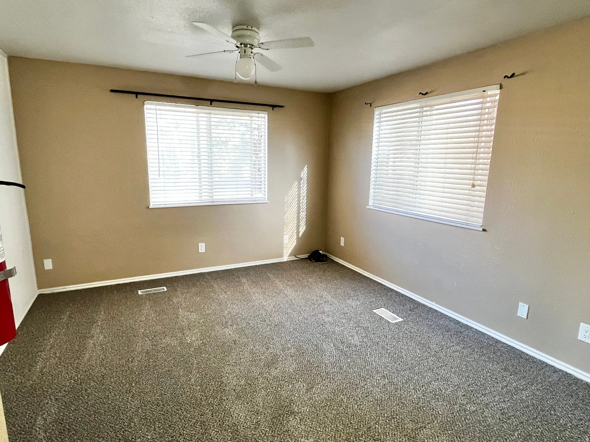 Carpeted interior space with two windows featuring horizontal blinds
