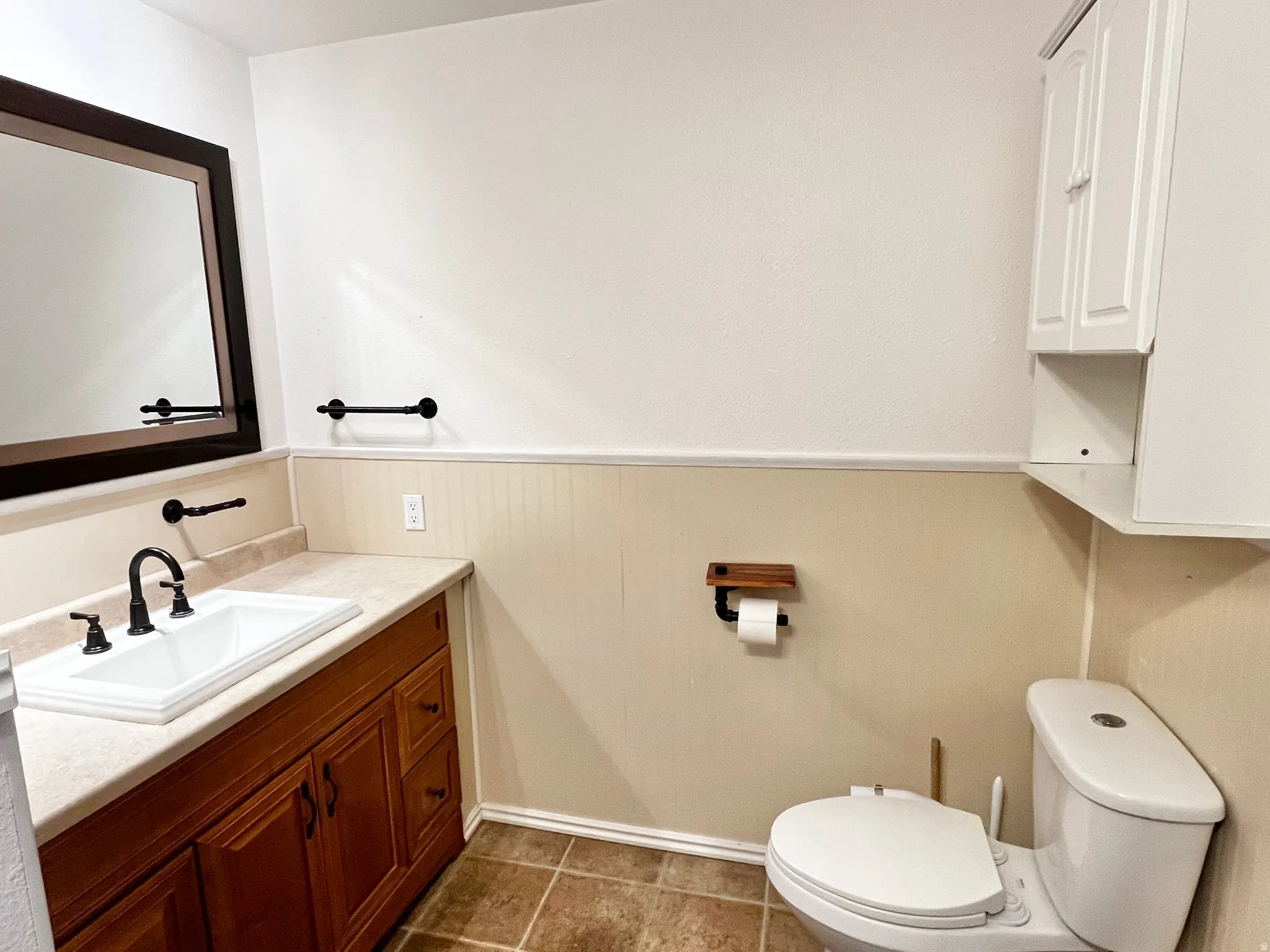 Bathroom featuring a wood-finish vanity with a light-toned countertop and integrated sink