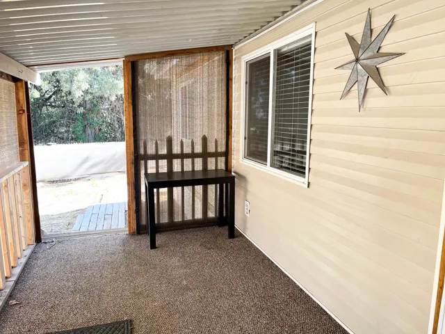 Enclosed outdoor space featuring a textured carpet floor, a horizontal slat ceiling, and a window with horizontal blinds