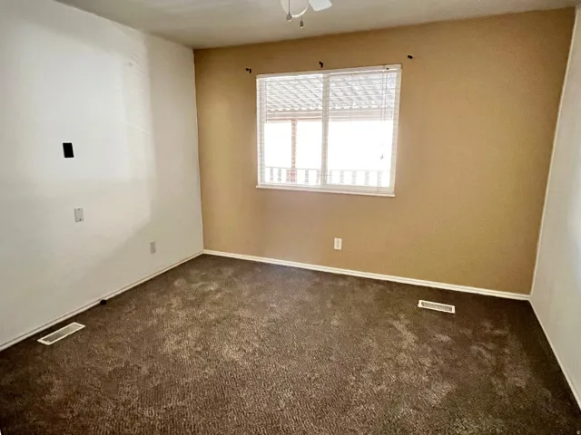 Carpeted room with a window featuring blinds and a white frame
