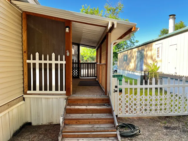 Wood-finish steps leading to a screened-in porch with a white picket fence and lattice gate